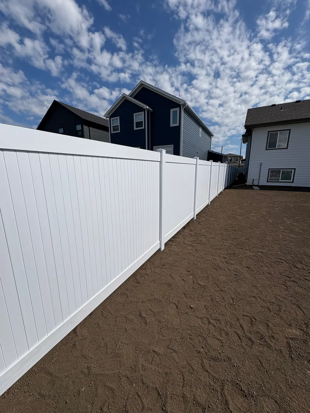 New white vinyl privacy fence along a backyard