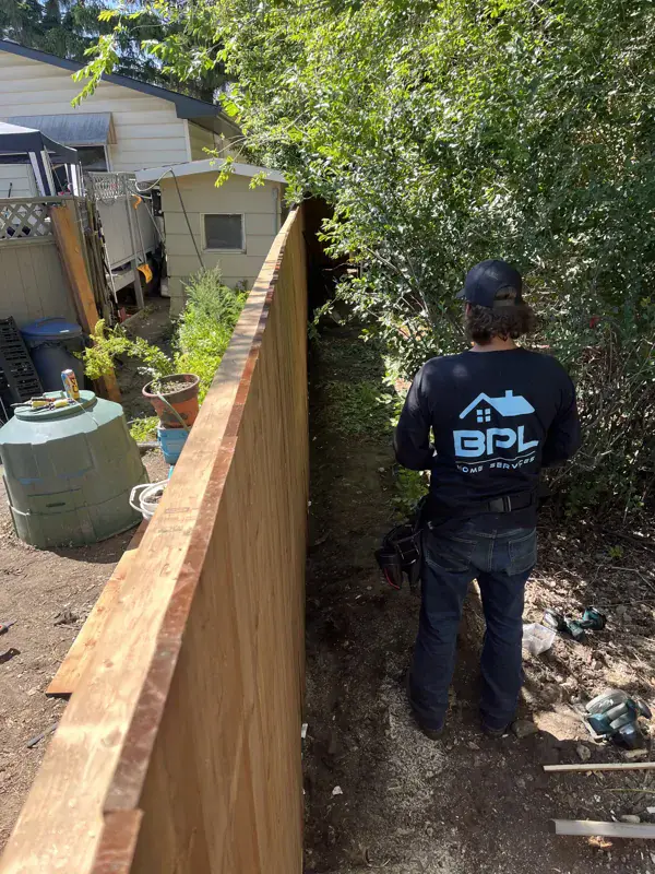BPL crew member beside a new cedar fence