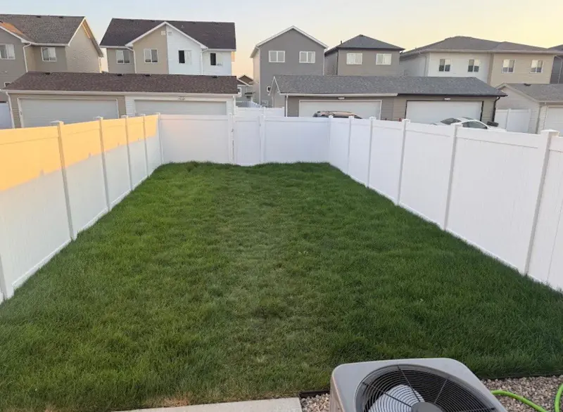 White vinyl privacy fence around a backyard lawn